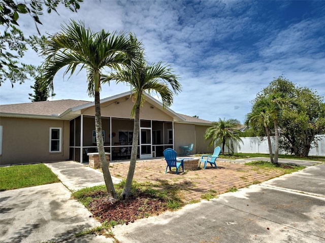 23102 Madelyn Ave, Port Charlotte, FL 33954 - rear view of house featuring a sunroom, an outdoor fire pit, stucco siding, and a patio area