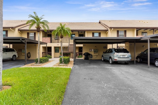 340 Three Lakes Ln Unit F, Venice, FL 34285 - view of front of house with a tile roof, covered parking, stucco siding, stairway, and a front lawn