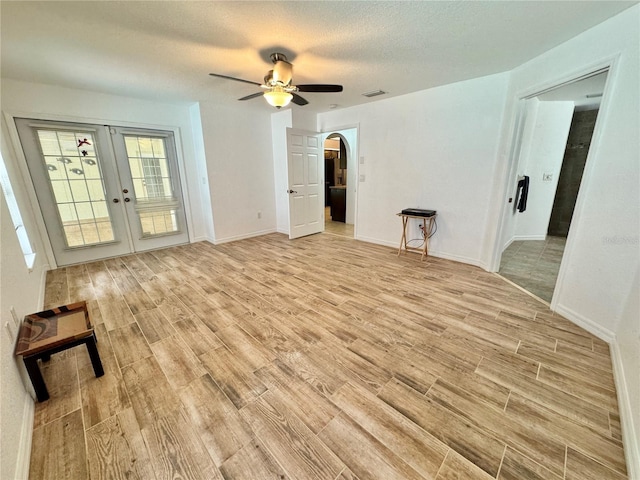 6522 Pimlico St, North Port, FL 34291 - unfurnished living room with light wood-style flooring, a ceiling fan, french doors, arched walkways, and a textured ceiling