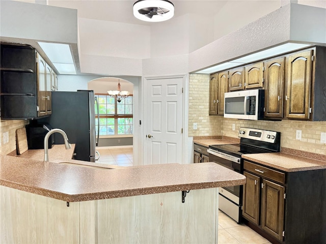 6522 Pimlico St, North Port, FL 34291 - kitchen featuring appliances with stainless steel finishes, light tile patterned floors, a chandelier, a peninsula, and tasteful backsplash