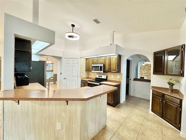 6522 Pimlico St, North Port, FL 34291 - kitchen featuring appliances with stainless steel finishes, arched walkways, backsplash, lofted ceiling, and light tile patterned floors