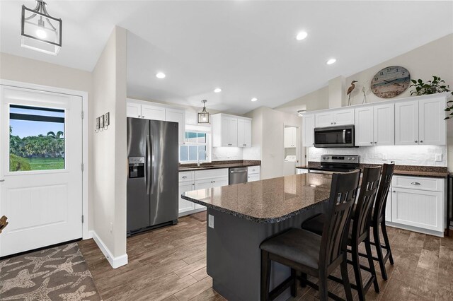 108 Albatross Rd, Rotonda West, FL 33947 - kitchen with appliances with stainless steel finishes, backsplash, a kitchen island, white cabinetry, and recessed lighting