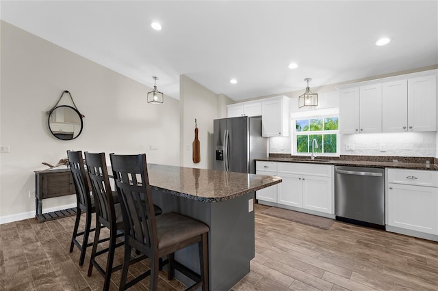 108 Albatross Rd, Rotonda West, FL 33947 - kitchen with appliances with stainless steel finishes, white cabinetry, a kitchen island, dark wood-type flooring, and a breakfast bar