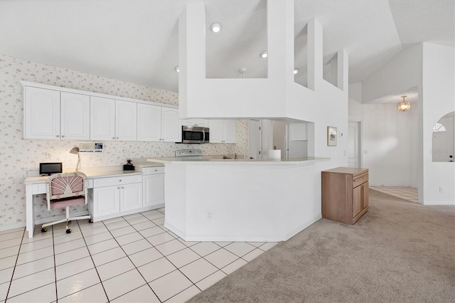 1429 Turnberry Dr, Venice, FL 34292 - kitchen with stainless steel microwave, white cabinets, high vaulted ceiling, light countertops, and wallpapered walls