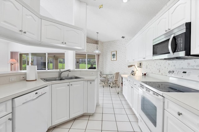 1429 Turnberry Dr, Venice, FL 34292 - kitchen with white appliances, wallpapered walls, light tile patterned floors, white cabinetry, and light countertops