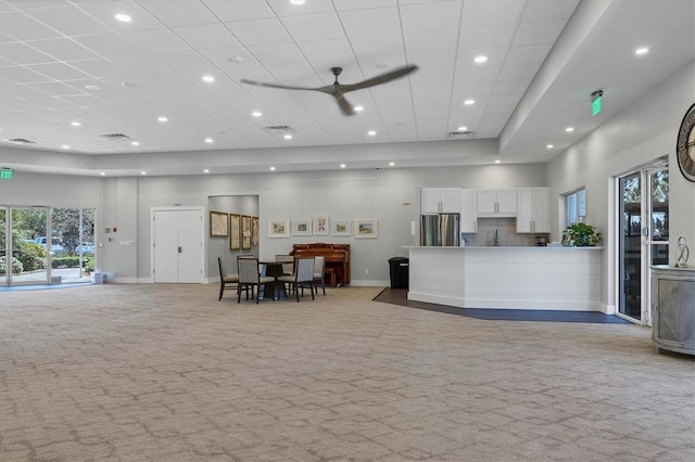 1429 Turnberry Dr, Venice, FL 34292 - kitchen with stainless steel refrigerator, open floor plan, light colored carpet, white cabinetry, and a high ceiling