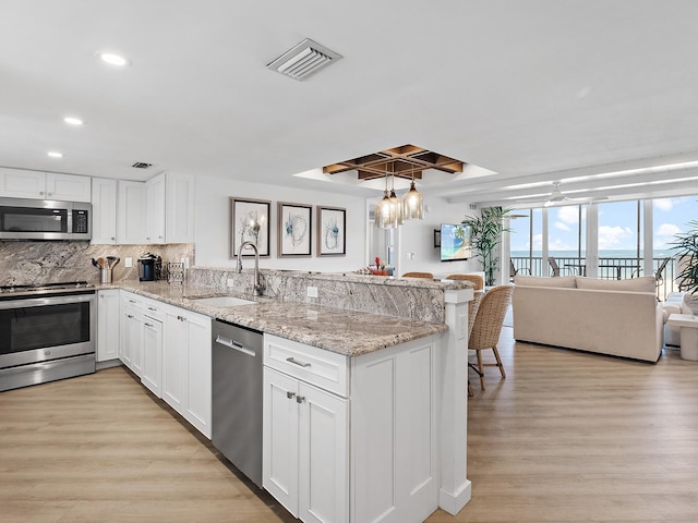 6300 Midnight Pass Rd Unit 809, Sarasota, FL 34242 - kitchen with stainless steel appliances, a peninsula, recessed lighting, light wood finished floors, and white cabinetry