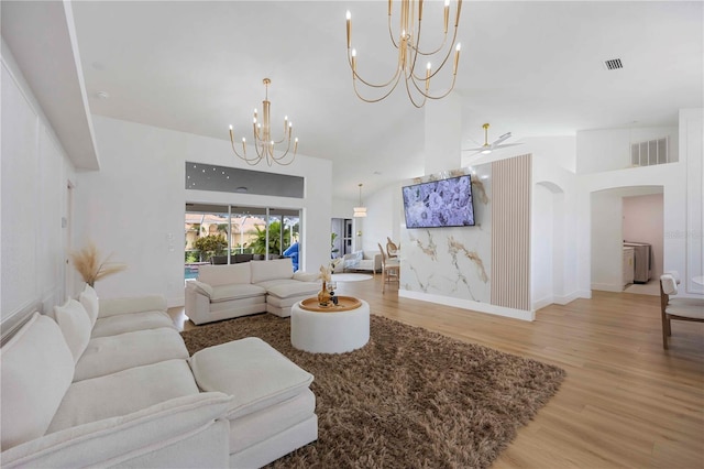 5028 Greenway Ct, North Port, FL 34287 - living room with a chandelier, light wood-style flooring, arched walkways, a high ceiling, and ceiling fan