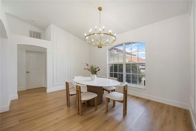 5028 Greenway Ct, North Port, FL 34287 - dining room featuring a chandelier, light wood finished floors, arched walkways, and lofted ceiling