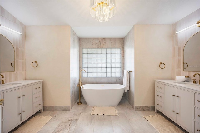 5028 Greenway Ct, North Port, FL 34287 - bathroom featuring a soaking tub, two vanities, a chandelier, tile walls, and marble look tiles