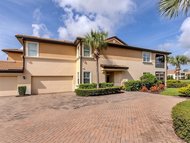 141 Bella Vista Ter Unit 34B, North Venice, FL 34275 - mediterranean / spanish-style home with decorative driveway, stucco siding, a tiled roof, and an attached garage