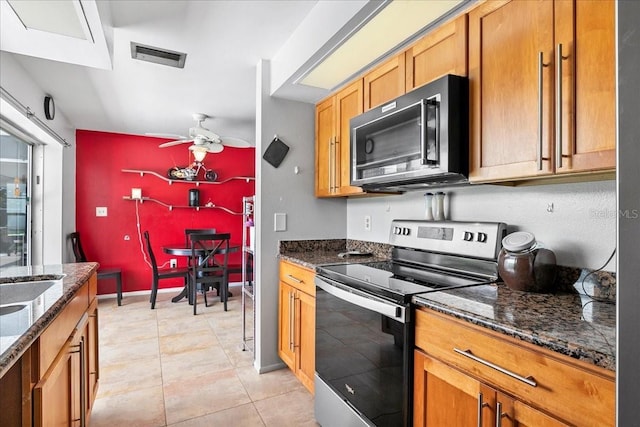 18671 Macgill Ave, Port Charlotte, FL 33948 - kitchen featuring stainless steel electric stove, black microwave, a ceiling fan, dark stone countertops, and brown cabinetry