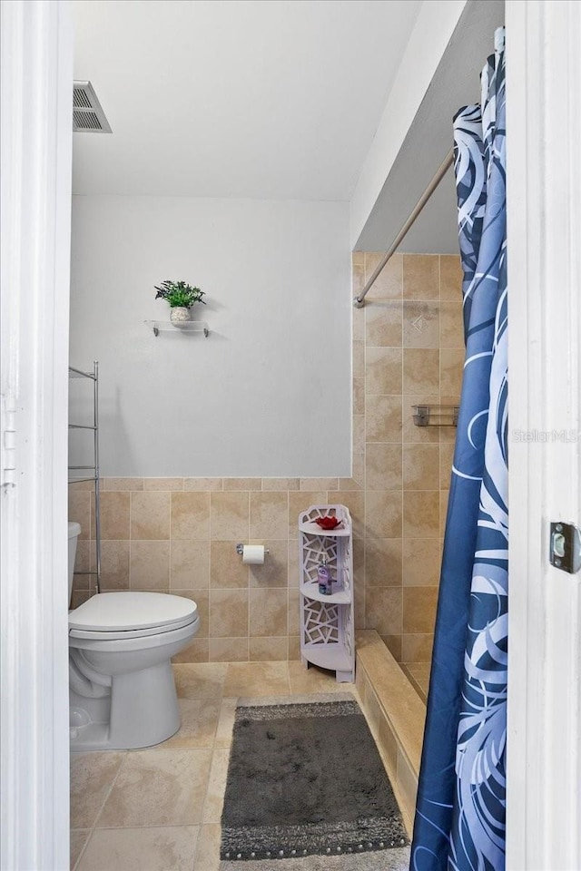 18671 Macgill Ave, Port Charlotte, FL 33948 - full bath featuring tile walls, a tile shower, a wainscoted wall, and tile patterned flooring