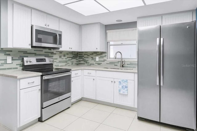 8651 Ellesmere Ct, North Port, FL 34287 - kitchen featuring appliances with stainless steel finishes, light countertops, tasteful backsplash, light tile patterned flooring, and white cabinetry
