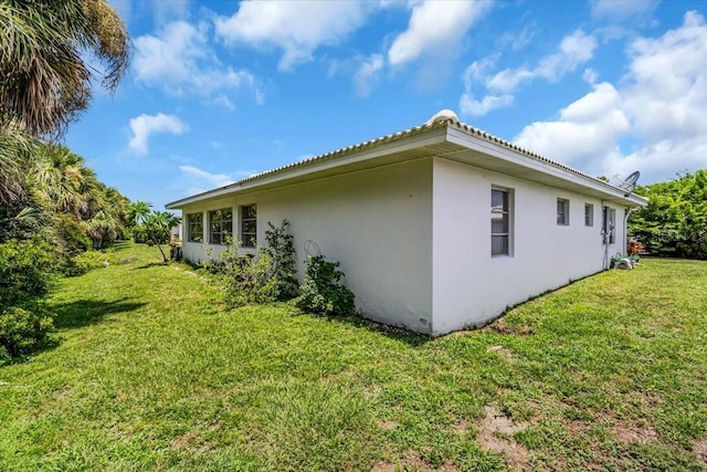 8651 Ellesmere Ct, North Port, FL 34287 - view of side of home featuring stucco siding and a lawn