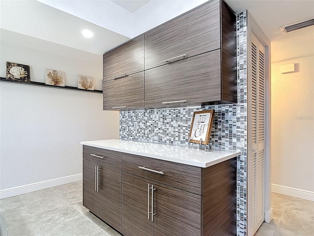 1335 Rock Dove Ct Unit 111, Punta Gorda, FL 33950 - kitchen featuring decorative backsplash, modern cabinets, light countertops, light tile patterned floors, and dark brown cabinetry