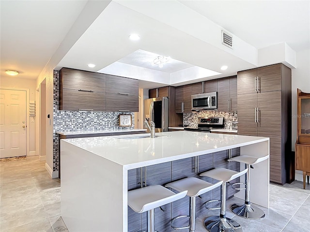 1335 Rock Dove Ct Unit 111, Punta Gorda, FL 33950 - kitchen featuring stainless steel appliances, a breakfast bar area, modern cabinets, decorative backsplash, and light countertops