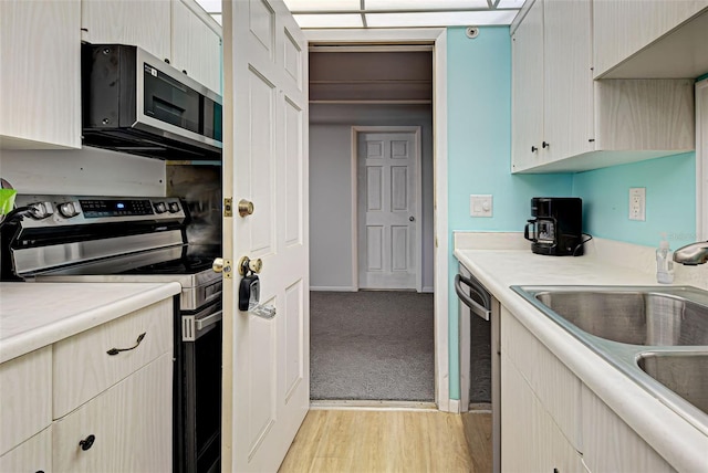 200 The Esplanade N Unit B19, Venice, FL 34285 - kitchen featuring stainless steel appliances, light countertops, light wood-style floors, and light carpet