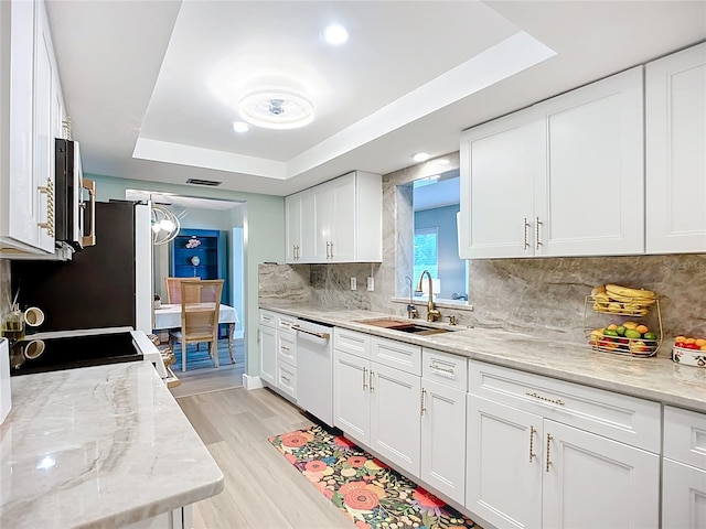 3274 Savage Rd, Sarasota, FL 34231 - kitchen featuring white dishwasher, a tray ceiling, white cabinets, light wood-type flooring, and tasteful backsplash