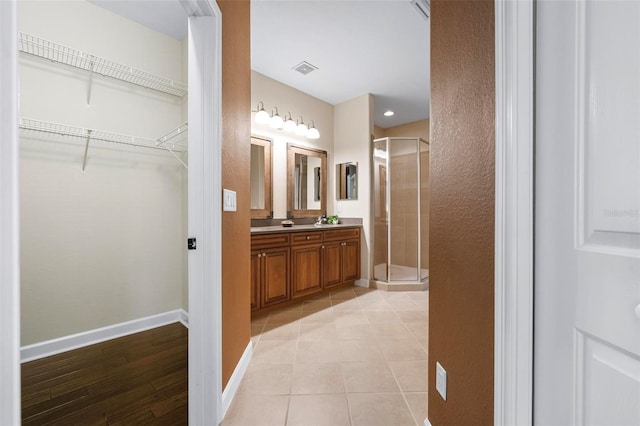 114 Bella Vista Ter Unit 6C, Nokomis, FL 34275 - bathroom featuring double vanity, a stall shower, a spacious closet, and tile patterned floors
