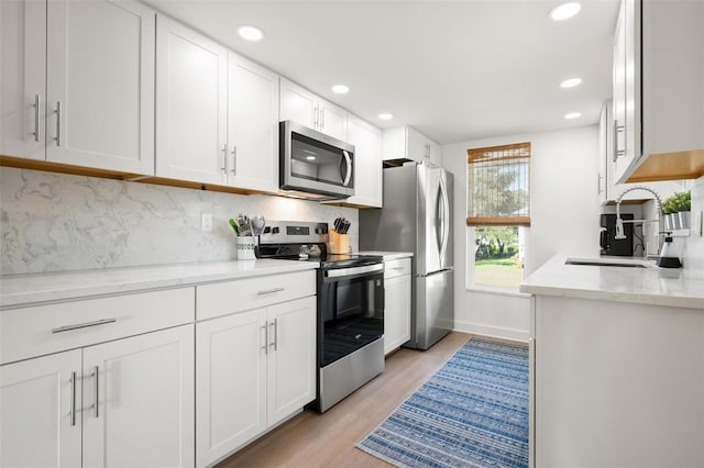 812 Garland Ave, Nokomis, FL 34275 - kitchen featuring stainless steel appliances, recessed lighting, light wood finished floors, backsplash, and white cabinets