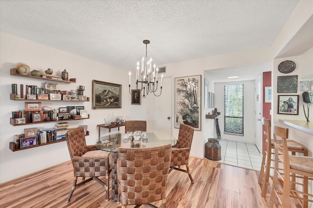 1088 Bird Bay Way Unit 307, Venice, FL 34285 - dining space featuring wood finished floors, a chandelier, and a textured ceiling