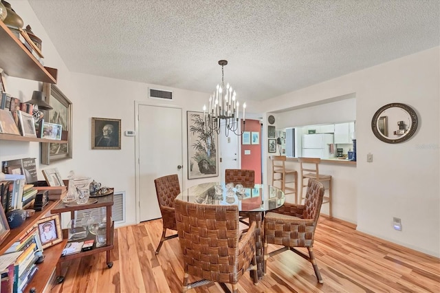 1088 Bird Bay Way Unit 307, Venice, FL 34285 - dining area with a chandelier, light wood-style floors, and a textured ceiling