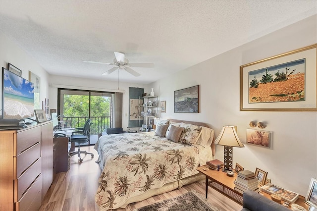1088 Bird Bay Way Unit 307, Venice, FL 34285 - bedroom featuring access to exterior, a textured ceiling, wood finished floors, and a ceiling fan