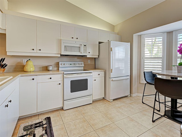 903 Addington Ct Unit 203, Venice, FL 34293 - kitchen with white appliances, vaulted ceiling, light countertops, light tile patterned floors, and white cabinetry