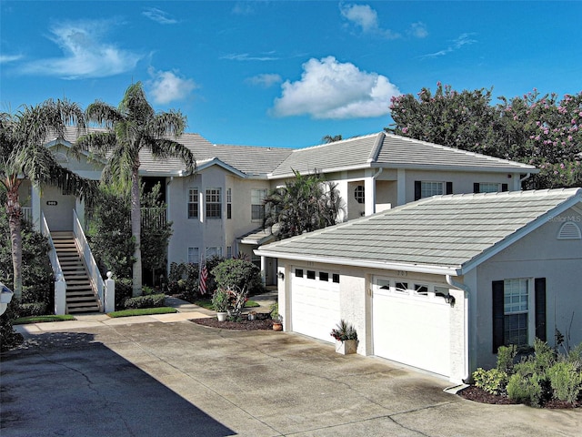 903 Addington Ct Unit 203, Venice, FL 34293 - view of front of home with a tiled roof, stucco siding, concrete driveway, a garage, and stairway