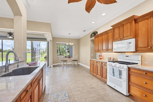 2471 Silver Palm Rd, North Port, FL 34288 - kitchen with white appliances, ceiling fan, tasteful backsplash, brown cabinetry, and light stone counters