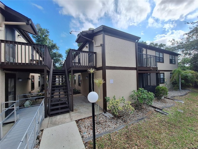 4022 Beaver Ln Unit 1000G, Port Charlotte, FL 33952 - view of side of home with stucco siding, stairs, a wooden deck, and a patio
