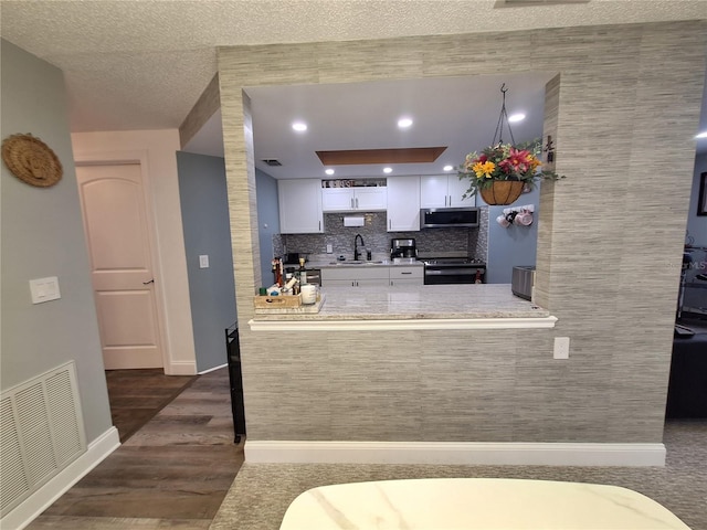 4022 Beaver Ln Unit 1000G, Port Charlotte, FL 33952 - kitchen with stainless steel microwave, black range with electric stovetop, dark wood-style flooring, white cabinets, and light countertops