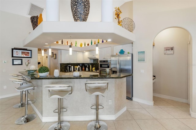 5001 Almar Dr, Punta Gorda, FL 33950 - kitchen with stainless steel appliances, arched walkways, a towering ceiling, white cabinetry, and a kitchen bar