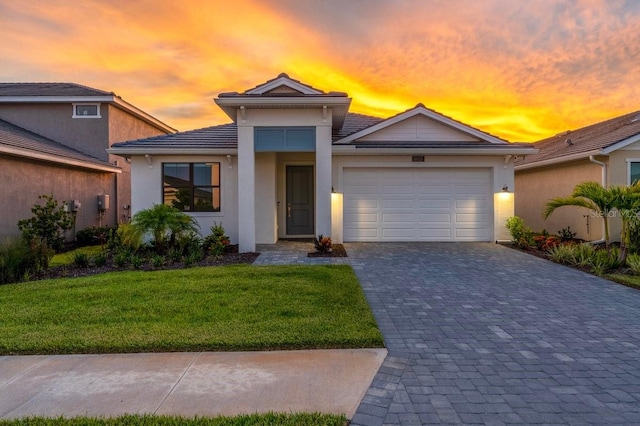 18525 Midsummer Pl, Venice, FL 34293 - view of front of house featuring a yard, an attached garage, decorative driveway, stucco siding, and a tile roof