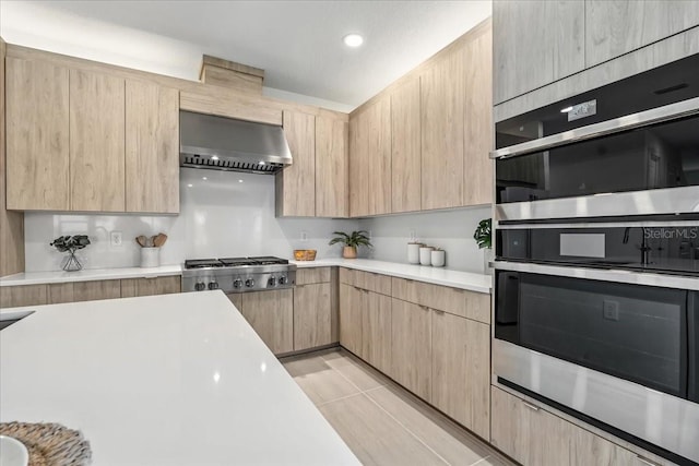 18525 Midsummer Pl, Venice, FL 34293 - kitchen with range hood, light brown cabinetry, appliances with stainless steel finishes, light countertops, and recessed lighting