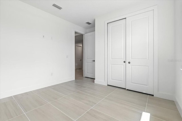 18525 Midsummer Pl, Venice, FL 34293 - unfurnished bedroom featuring light tile patterned floors and a closet