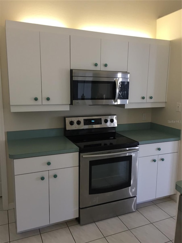 15140 Lyneburg Ave, Port Charlotte, FL 33981 - kitchen with stainless steel appliances, white cabinetry, and light tile patterned floors