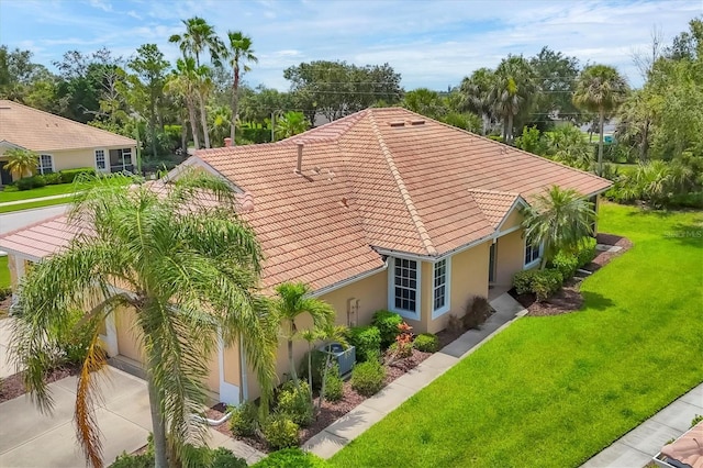 4841 Whispering Oaks Dr, North Port, FL 34287 - view of property exterior with a tiled roof, stucco siding, a yard, a garage, and driveway
