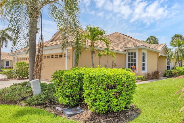 4841 Whispering Oaks Dr, North Port, FL 34287 - view of side of property featuring a garage, stucco siding, a tile roof, concrete driveway, and a lawn