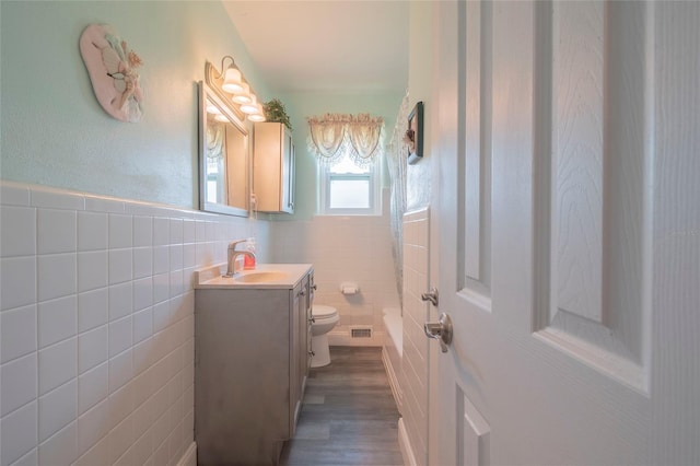 full bathroom with wood-type flooring, vanity, toilet, and tile walls