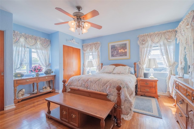 bedroom featuring ceiling fan, multiple windows, and light wood-type flooring