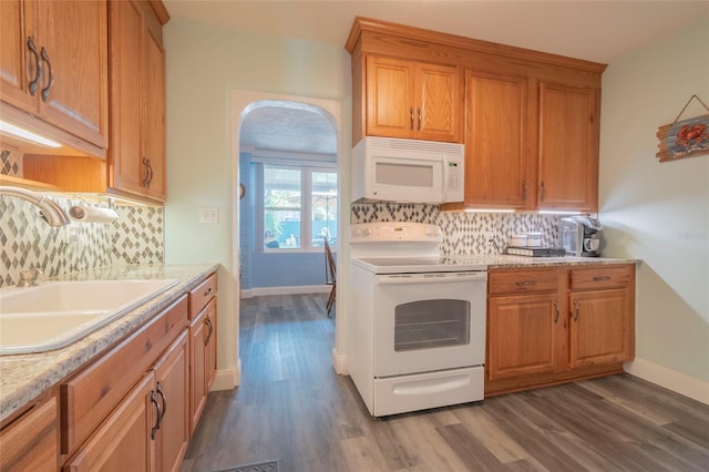 kitchen featuring backsplash, sink, white appliances, and dark hardwood / wood-style floors