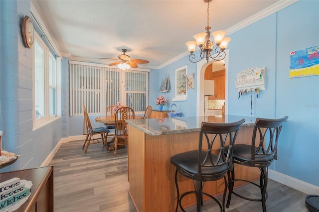 kitchen featuring crown molding, plenty of natural light, hardwood / wood-style floors, and decorative light fixtures