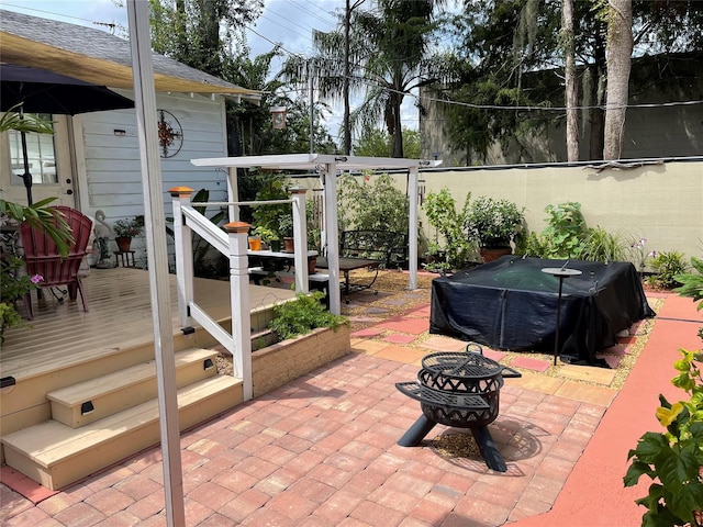 view of patio / terrace with a wooden deck, area for grilling, and a fire pit