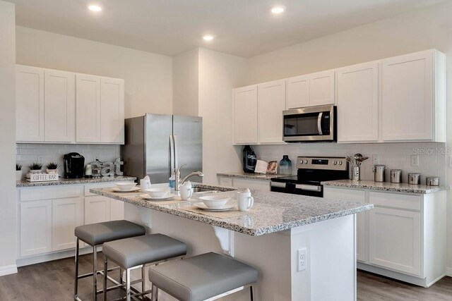 kitchen with a kitchen island with sink, white cabinetry, dark hardwood / wood-style floors, and stainless steel appliances