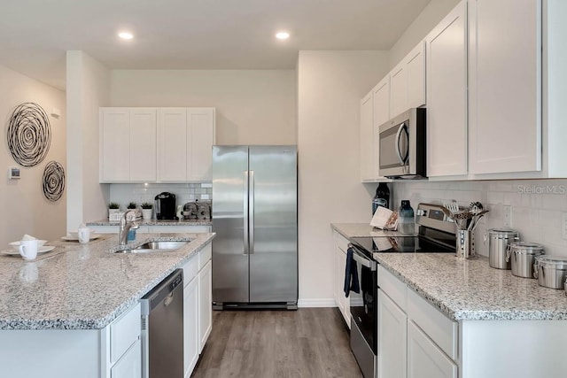 kitchen featuring backsplash, stainless steel appliances, white cabinets, and light wood-type flooring