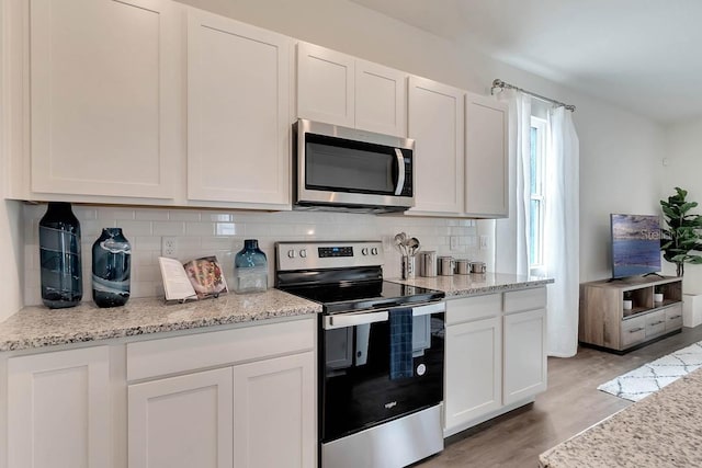 kitchen featuring tasteful backsplash, stainless steel appliances, white cabinets, and light wood-type flooring