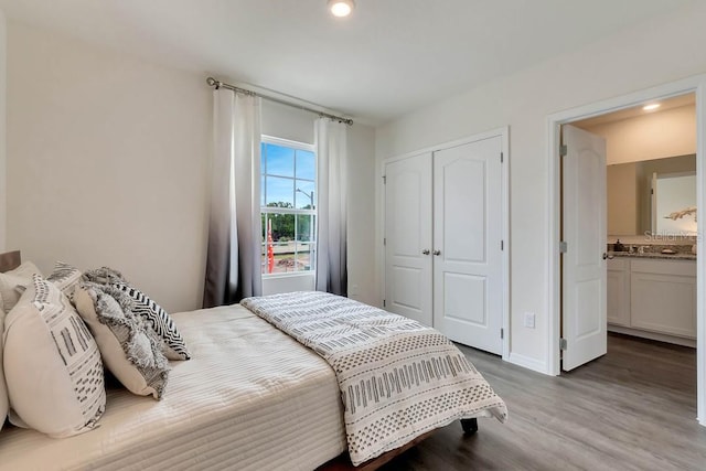 bedroom featuring a closet, connected bathroom, and hardwood / wood-style flooring