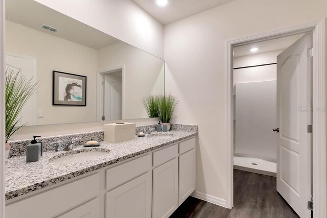 bathroom featuring double sink vanity, a shower, and hardwood / wood-style flooring